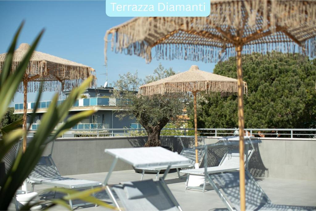 un patio avec une table, des chaises et un parasol dans l'établissement Residence I Diamanti - Siroli Collection, à Cervia