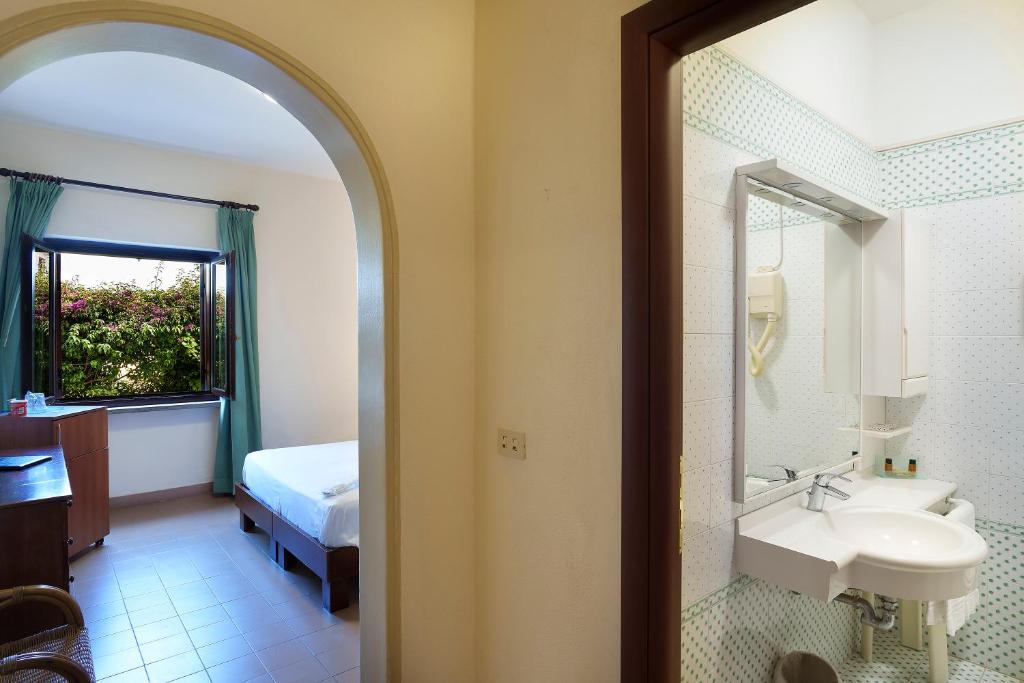une salle de bain avec un lavabo, un lit et un miroir dans l'établissement Hotel Le Dune, à Sabaudia 52 autres photos