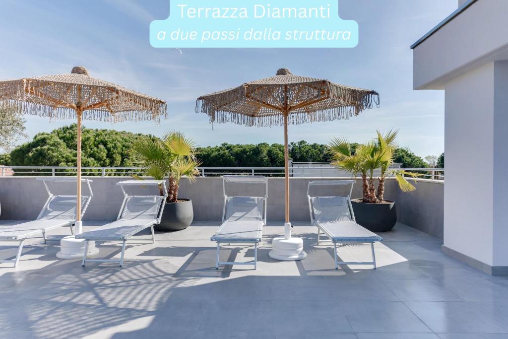 un groupe de chaises et de parasols sur un toit dans l'établissement Elegance Suite Apartments - Siroli Collection, à Cervia