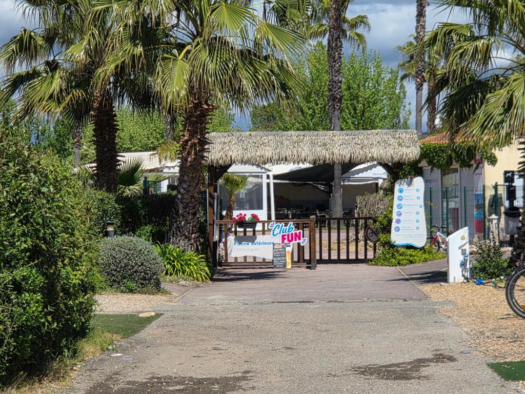 une porte menant à une maison avec des palmiers et un panneau dans l'établissement Fabuleux mobil-homme 4/6 personnes, à Fréjus