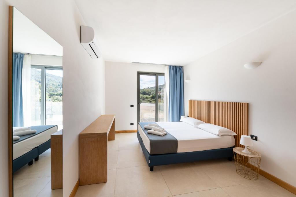 une chambre blanche avec un lit et une fenêtre dans l'établissement Hotel Delfino, à Procchio