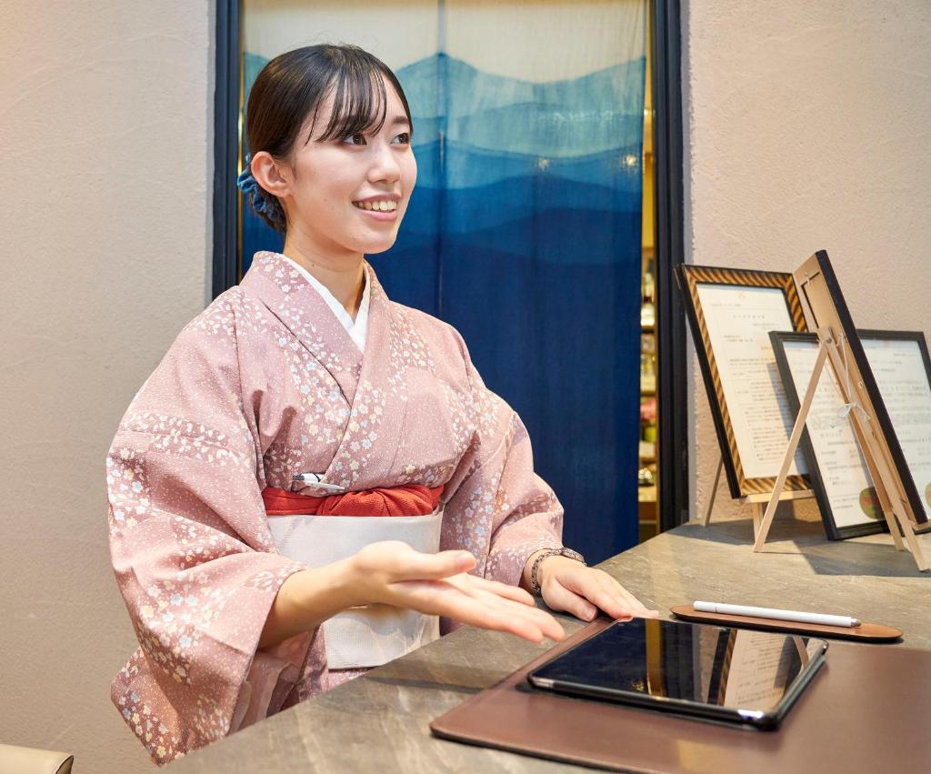 une femme en kimono assise à une table avec un ordinateur portable dans l'établissement Naruto Kaigetsu, à Naruto