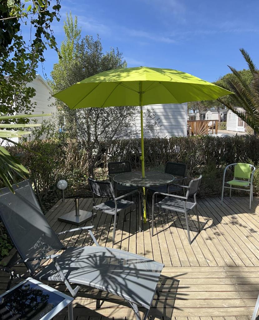- une table et des chaises avec un parasol vert sur la terrasse dans l'établissement Mobil-home de charme avec deux terrasses, à Vias