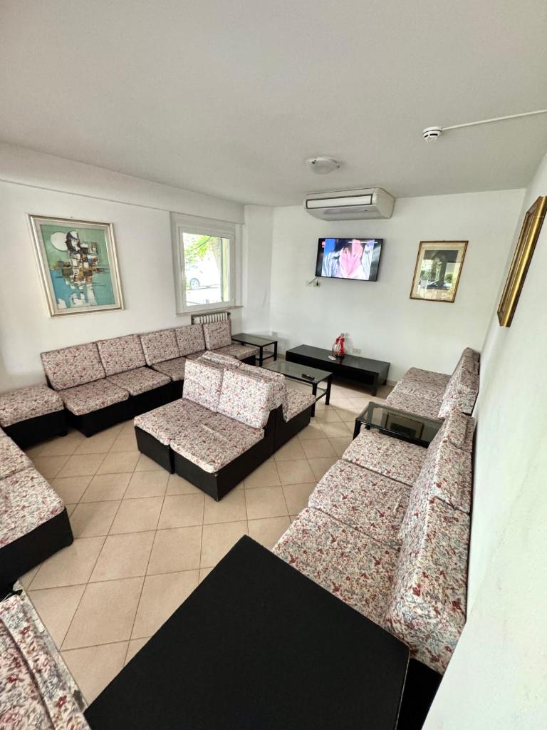 une salle d'attente avec des canapés et une télévision à écran plat dans l'établissement Hotel Urania Nuova Gestione, à Rimini