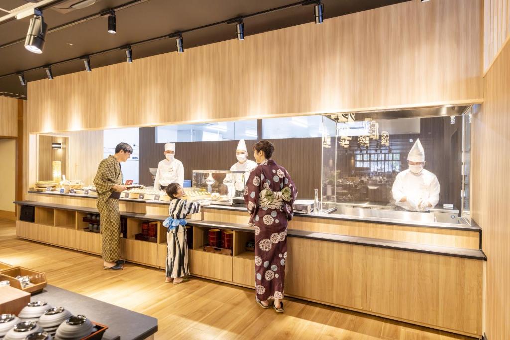 un groupe de personnes dans une cuisine préparant la nourriture dans l'établissement Ooedo Onsen Monogatari Premium Seiunkaku, à Awara