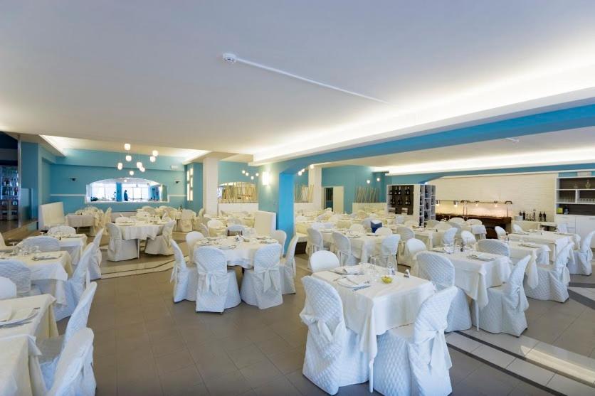 une salle de banquet avec des tables blanches et des chaises blanches dans l'établissement Hotel Eden Gigli, à Numana