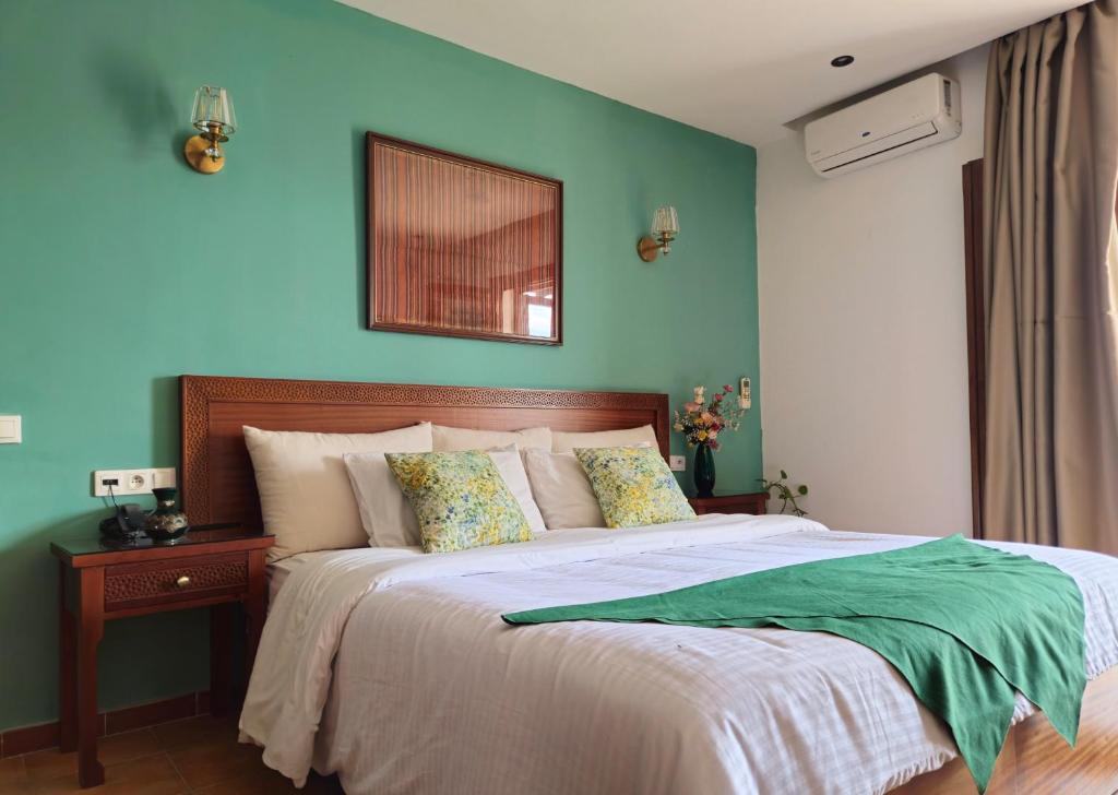 une chambre avec un grand lit avec un mur bleu dans l'établissement Riad Dar Achaach, à Tetouan