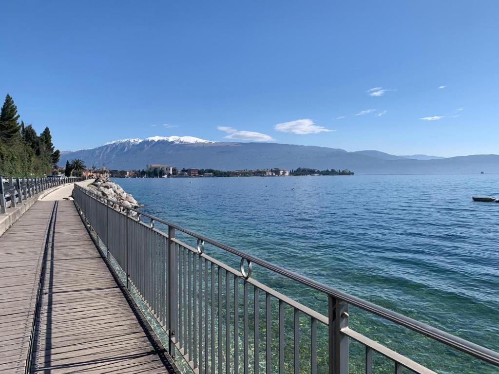 une promenade en bois à côté d'un plan d'eau dans l'établissement Residence Villa Alba room nr 415, à Gardone Riviera