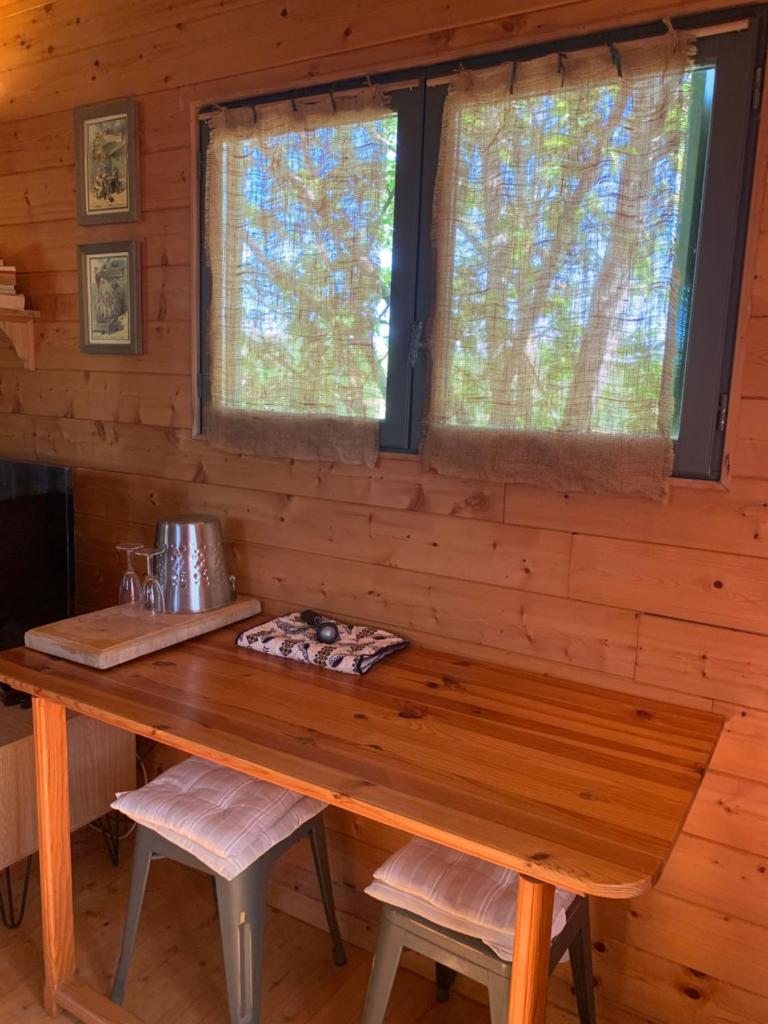 - une table en bois dans une cabine avec 2 fenêtres dans l'établissement Roulotte et Nature, à Mirepoix 10 autres photos