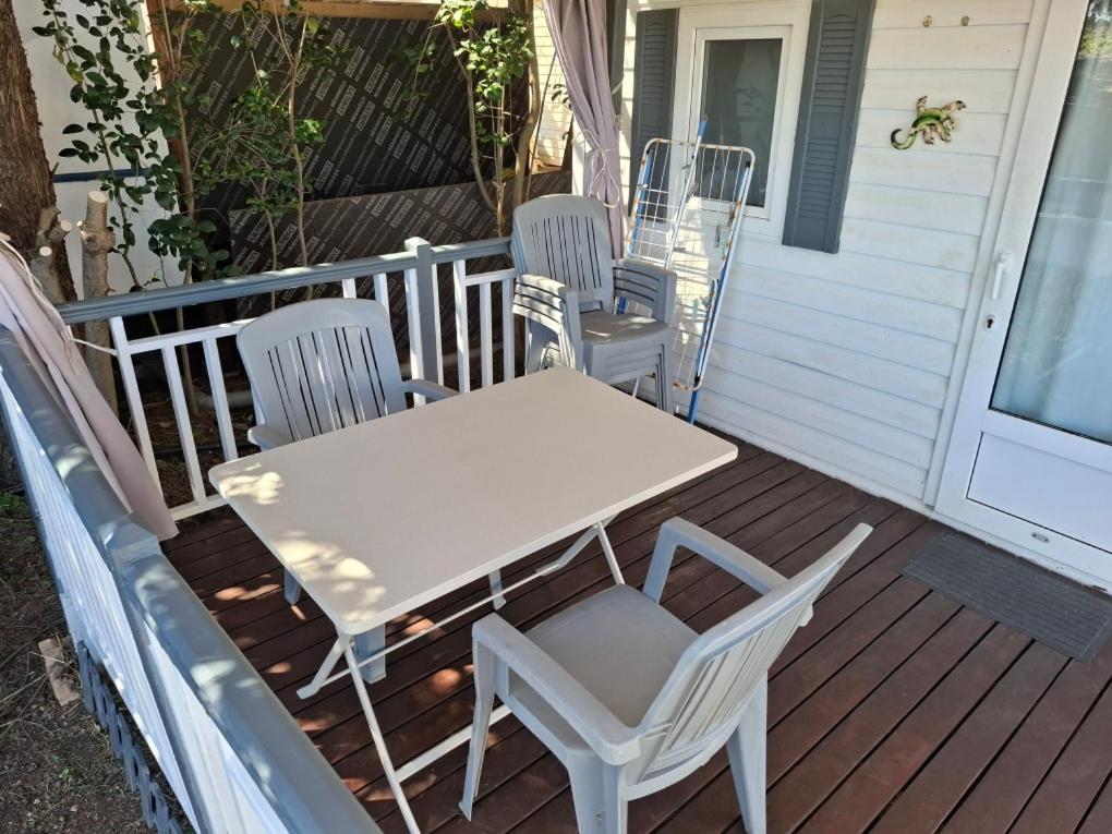 - une table et des chaises blanches sur une terrasse couverte dans l'établissement Mobil Home Camping New Day, à Vic-la-Gardiole