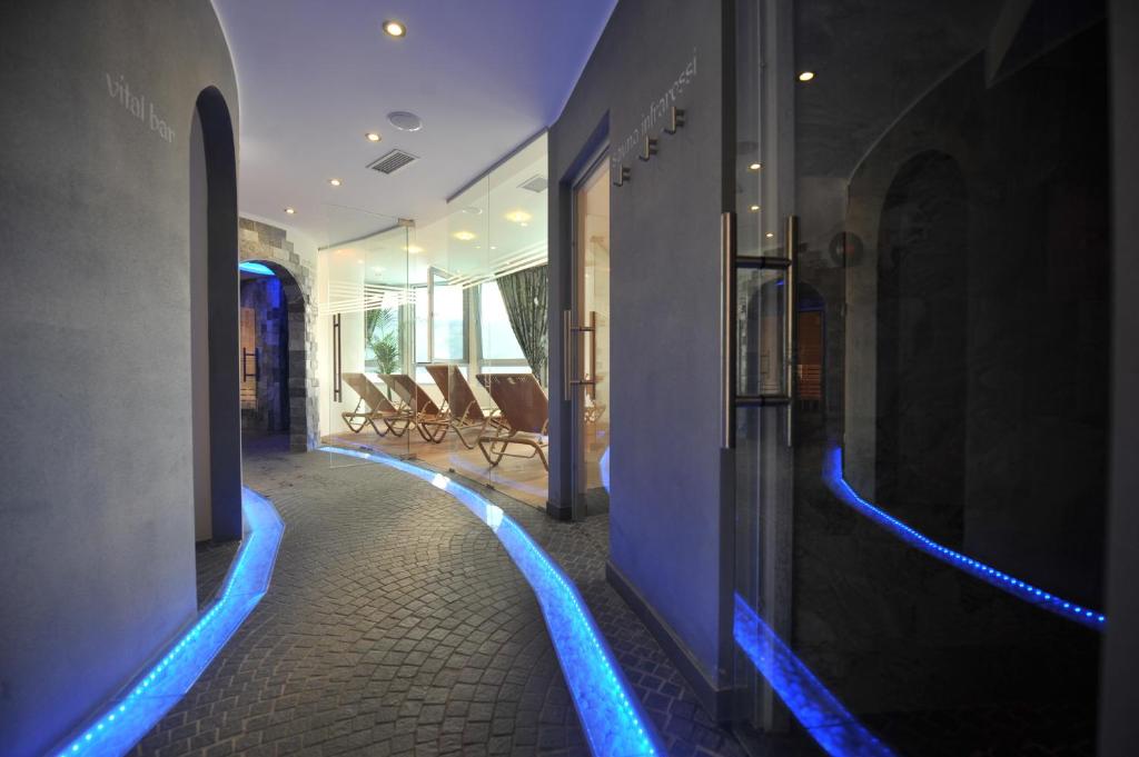 un couloir avec des lumières bleues sur le côté du bâtiment dans l'établissement Parc Hotel Du Lac, à Levico Terme