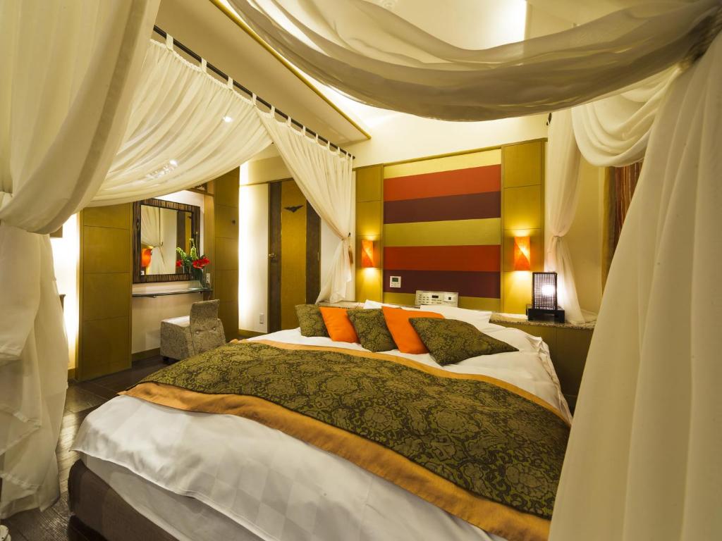 une chambre avec un grand lit avec des oreillers orange dans l'établissement リゾートホテル CARA -Adult Only-, à Sasebo