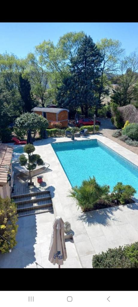 une grande piscine avec des parasols et une piscine dans l'établissement GITE 2 personnes avec piscine, à Le Bosc
