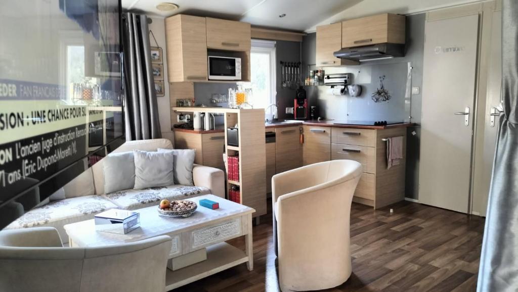 un salon avec un canapé et une table et une cuisine dans l'établissement Camping L'Oasis 5 étoiles à Puget-sur-Argens, à Puget-sur Argens 21 autres photos