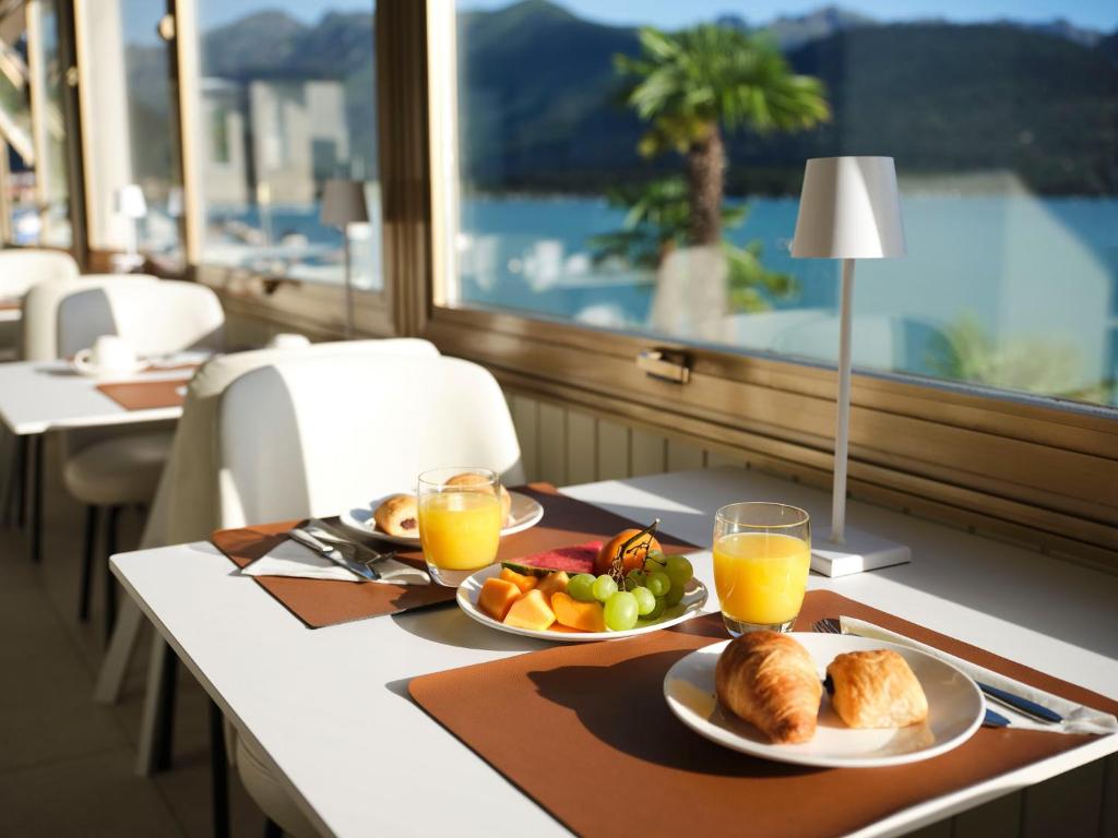 une table avec deux assiettes de nourriture et de jus d'orange dans l'établissement Hotel Carillon, à Baveno