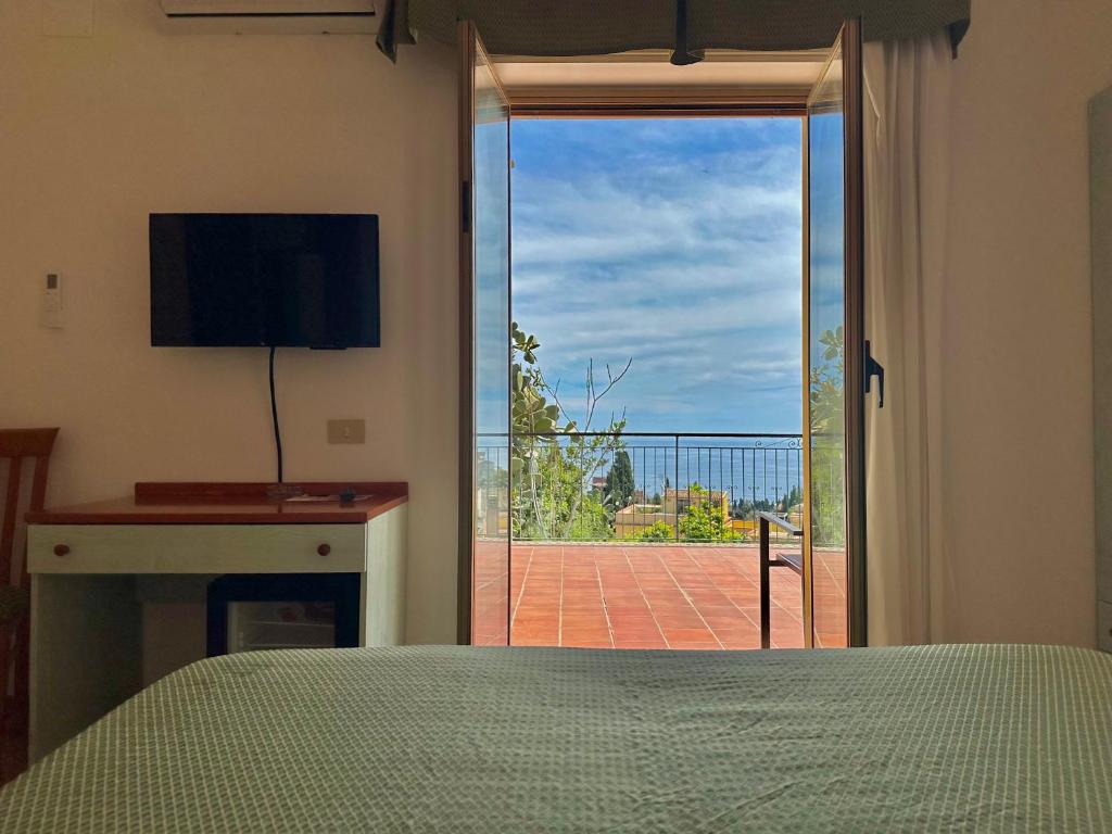 - une chambre avec un lit et une grande porte coulissante en verre dans l'établissement Hotel Soleado, à Taormine