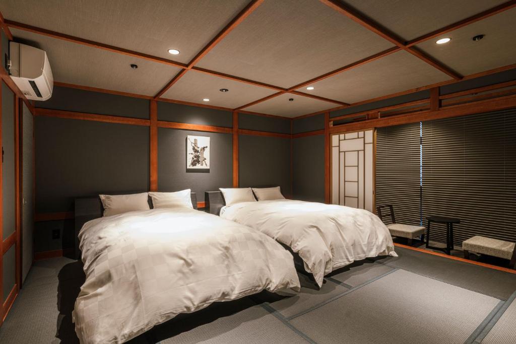 une chambre avec deux lits et une fenêtre dans l'établissement Shinzan Kinosaki, à Toyooka