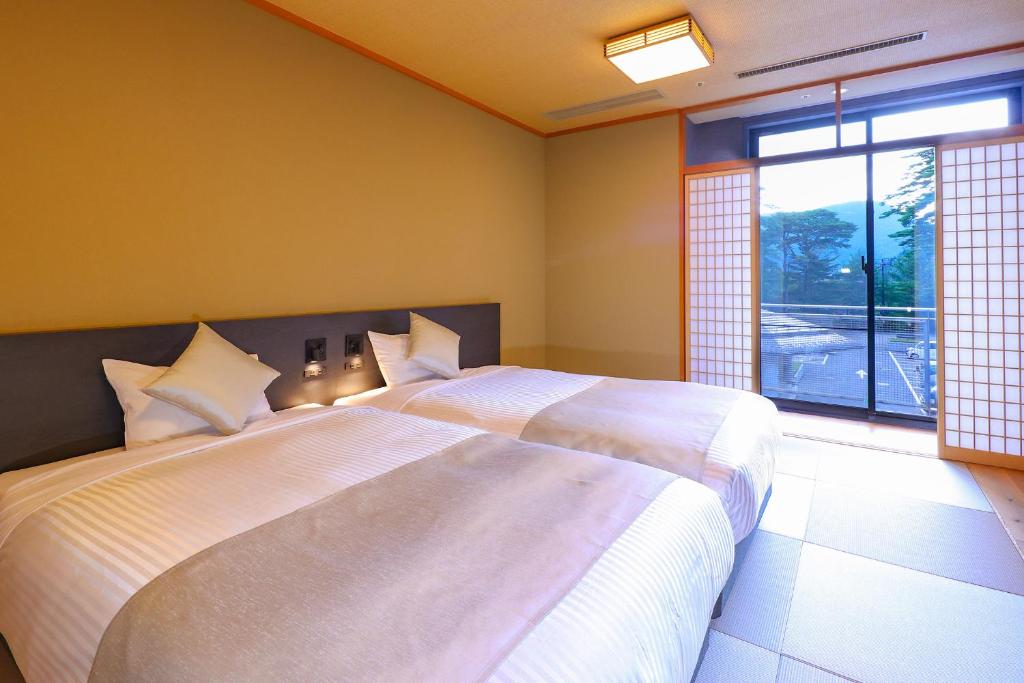 une chambre avec deux lits et une grande fenêtre dans l'établissement TAOYA Nasu Shiobara, à Nasushiobara