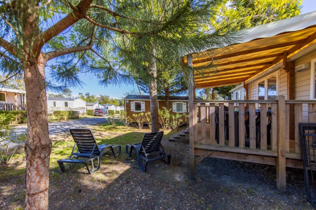 une terrasse couverte avec 2 chaises et une maison dans l'établissement Mobilhome Camping Siblu les Viviers, à Lège-Cap-Ferret