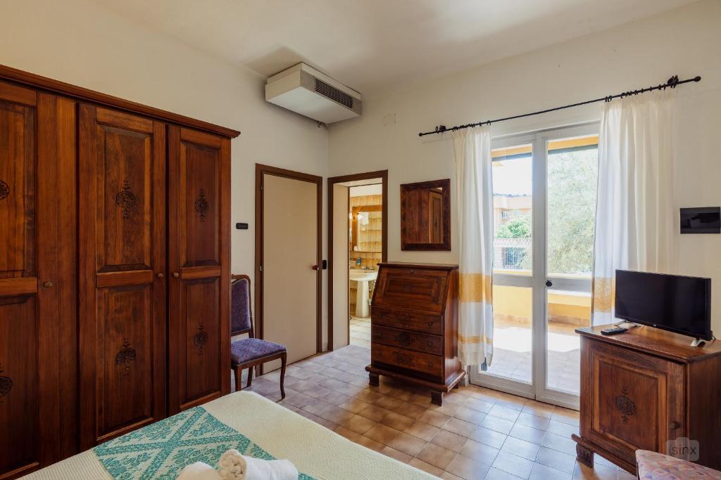 - une chambre avec un lit, une commode et une télévision dans l'établissement Hotel Malaspina, à Bosa Marina