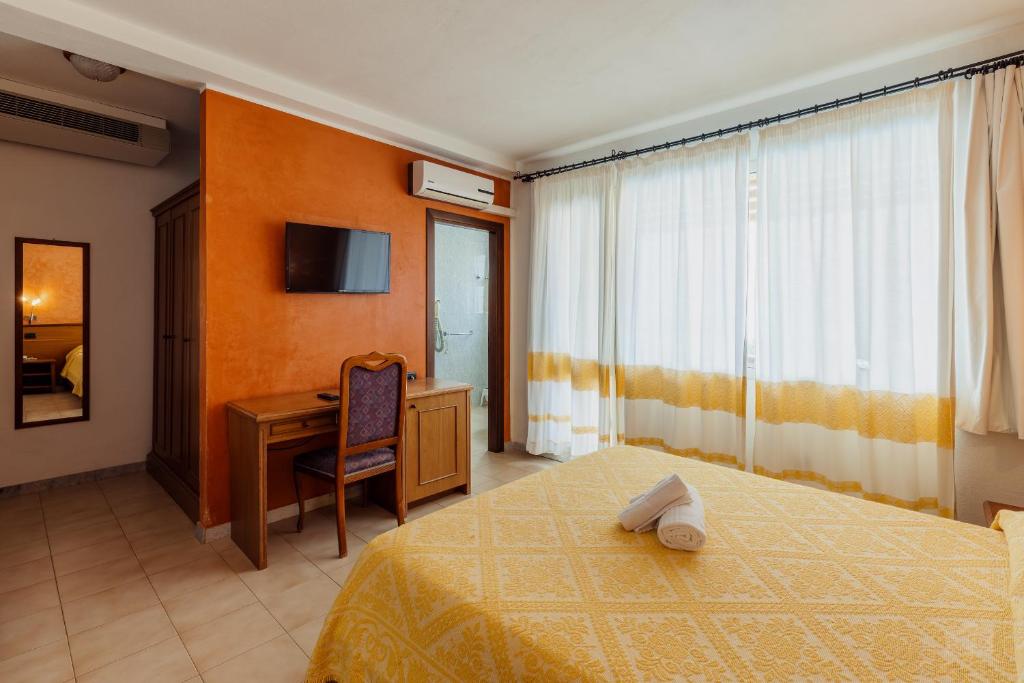 une chambre avec un lit, un bureau et une télévision dans l'établissement Hotel Malaspina, à Bosa Marina