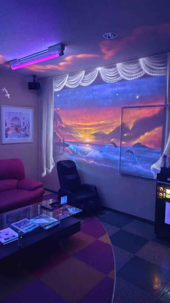 un salon avec un tableau représentant un coucher de soleil dans l'établissement hotel surfrider, à Wada-shinden