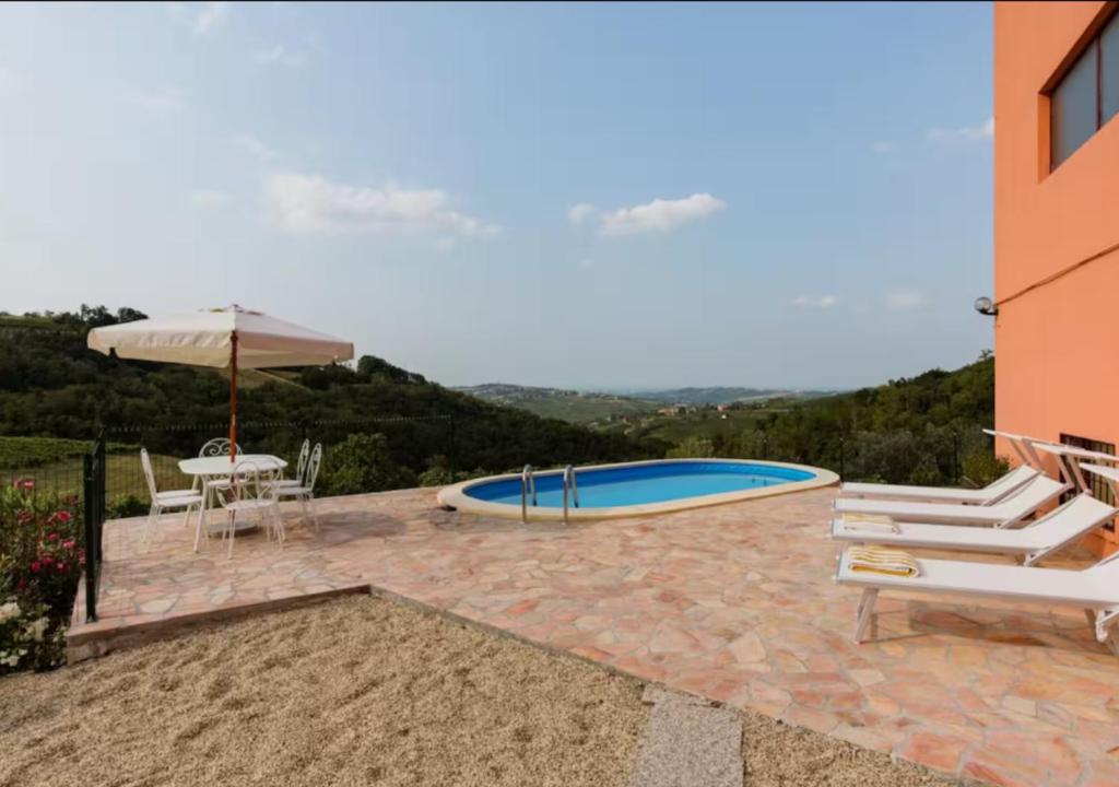 une terrasse avec une piscine, des chaises et un parasol dans l'établissement Villa Teresa - Villa & Piscina immersi nel vigneto!, à Montecalvo Versiggia