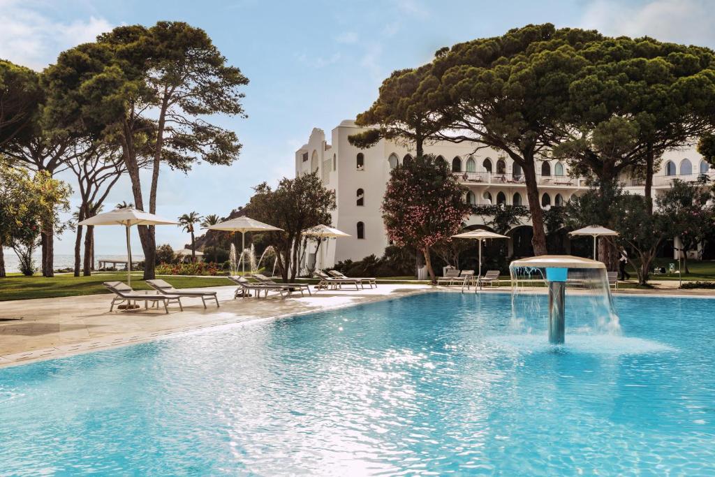 une piscine avec une fontaine en face d'un bâtiment dans l'établissement Falkensteiner Resort Capo Boi, à Villasimius