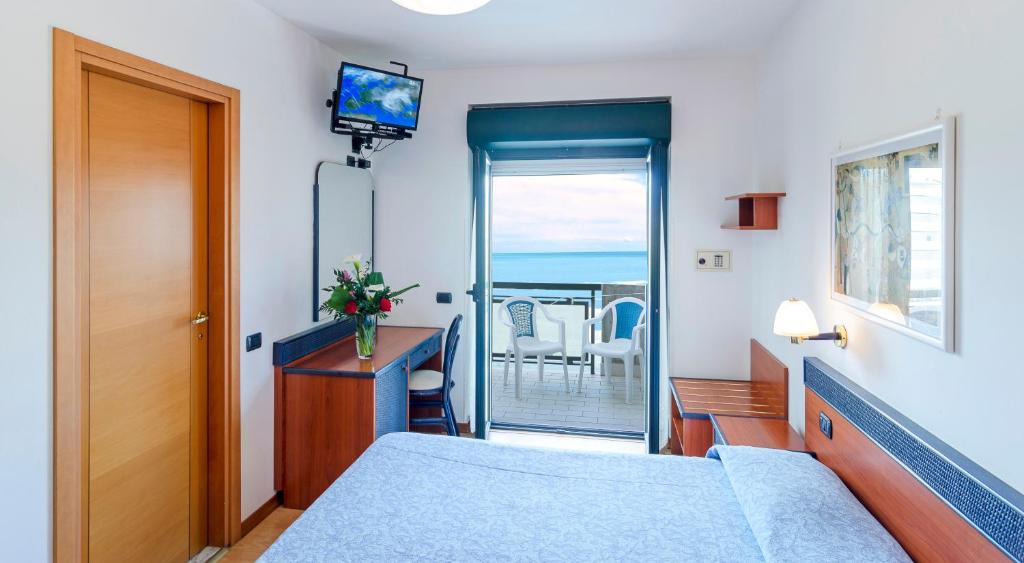 une chambre avec un lit et une télévision et un balcon dans l'établissement Hotel Tassoni Maison, à Alba Adriatica
