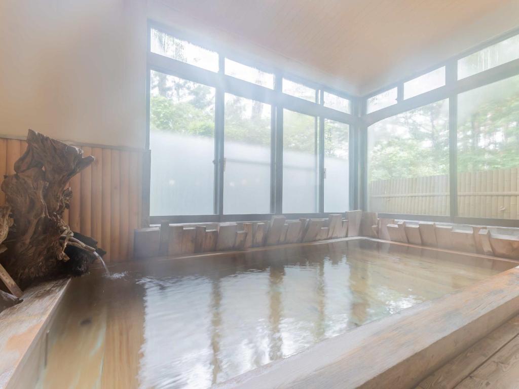 - une piscine d'eau dans une chambre avec fenêtres dans l'établissement 檜湯の宿　松伯, à Aoki-gemi