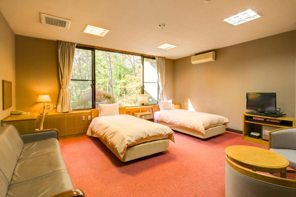 une chambre d'hôtel avec deux lits et une télévision dans l'établissement Lake Yamanakako Shuzansou, à Yamanakako