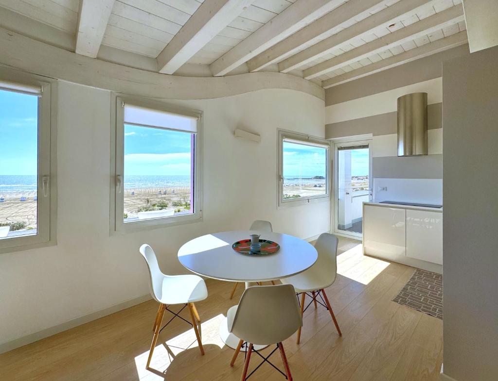 une salle à manger blanche avec une table et des chaises dans l'établissement Hotel Lux, à Caorle