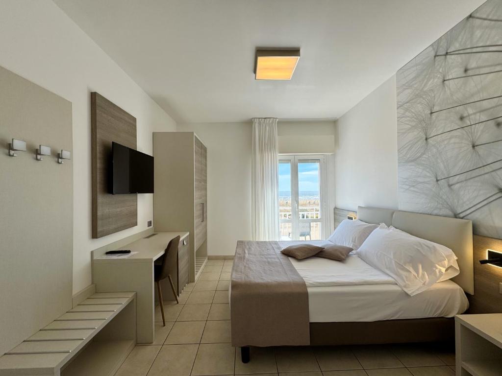 une chambre avec un lit, un bureau et une télévision dans l'établissement Hotel Lux, à Caorle