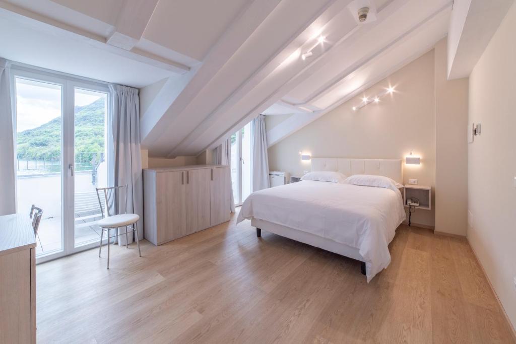 une chambre avec un lit blanc et une grande fenêtre dans l'établissement Hotel Due Palme, à Mergozzo
