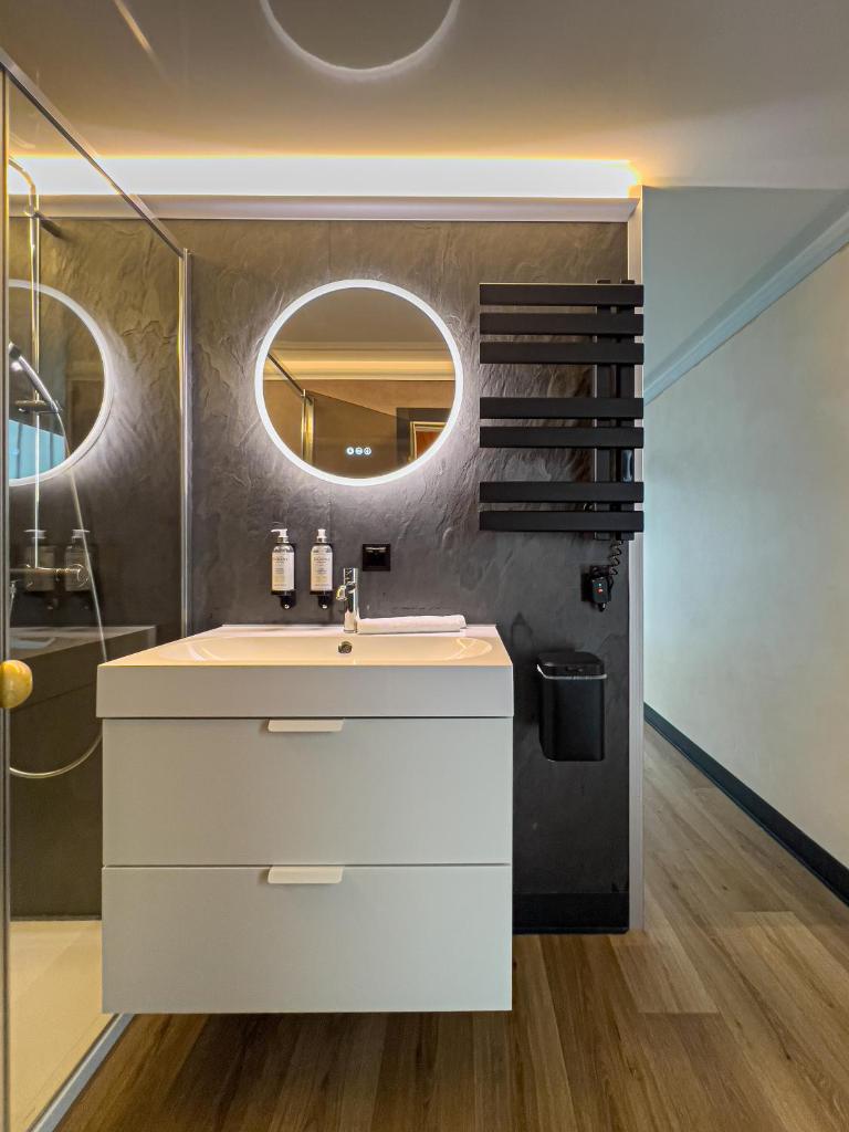 une salle de bain avec un lavabo blanc et un miroir dans l'établissement L'Escale Royale Saverne - Rhin - Strasbourg, à Saverne