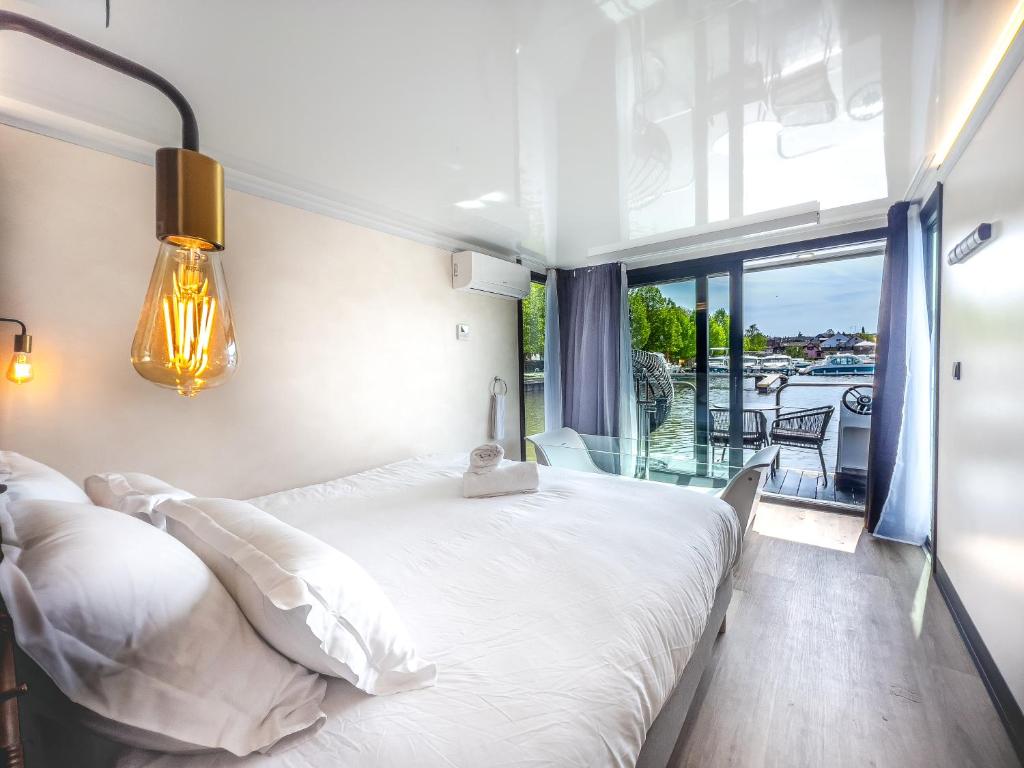 une chambre avec un grand lit blanc et un balcon dans l'établissement L'Escale Royale Saverne - Rhin - Strasbourg, à Saverne