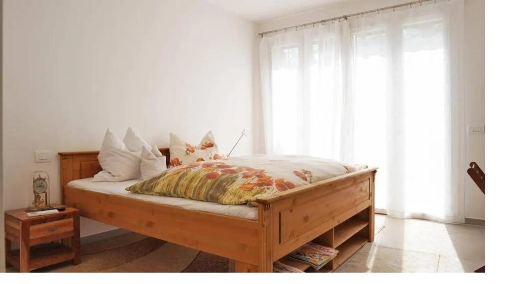 une chambre avec un lit en bois aux murs blancs dans l'établissement Villa Petra, à Imperia