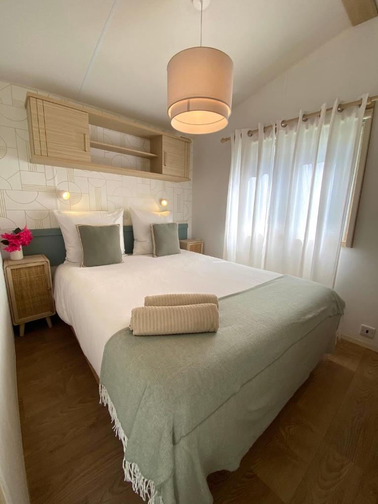 - une chambre avec un grand lit blanc et des rideaux blancs dans l'établissement Bungalow Camping Parc Montana, à Gassin