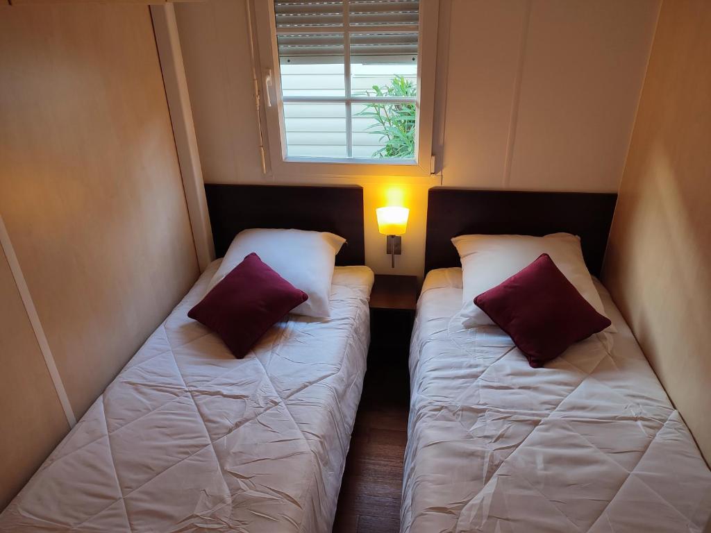 deux lits dans une petite pièce avec une fenêtre dans l'établissement Grand MOBIL HOME Spatieux 40m2 - 2 Ch, à Argelès-sur-Mer