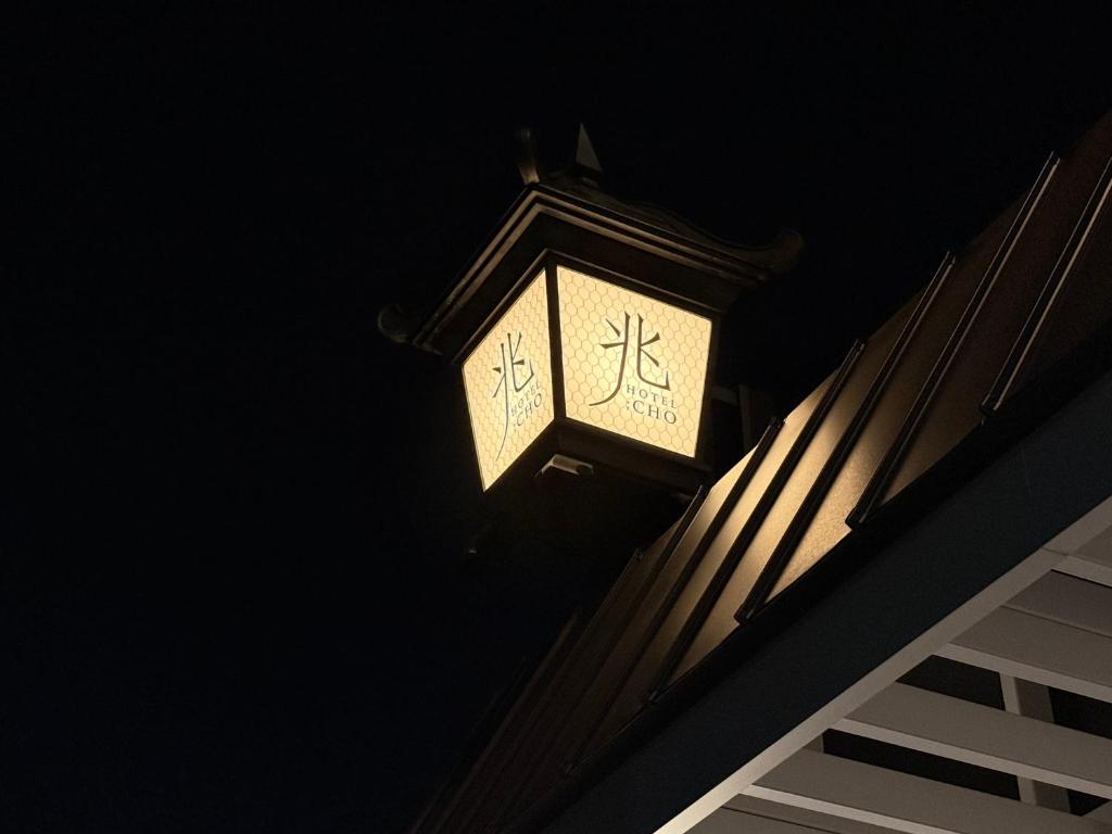une horloge sur le côté du bâtiment la nuit dans l'établissement ホテル 兆 各務原店 Hotel CHO Kakamigahara, à Kakamigahara