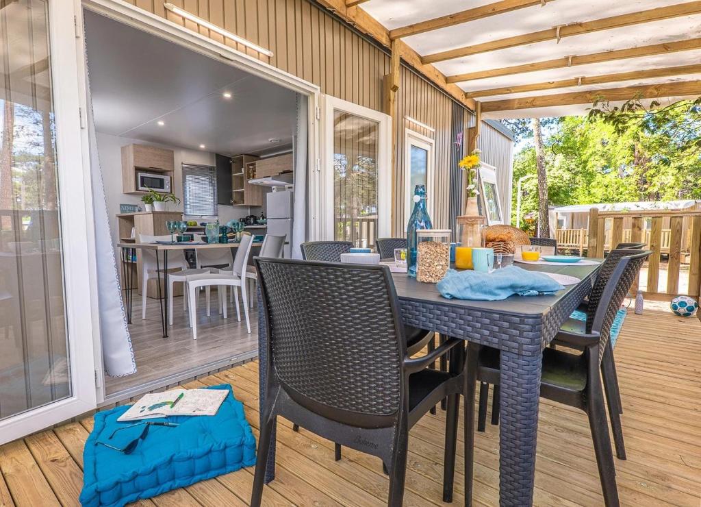 une salle à manger avec une table et des chaises sur un patio dans l'établissement CAMPING Bassin Arcachon - LES GOELANDS, à Arès