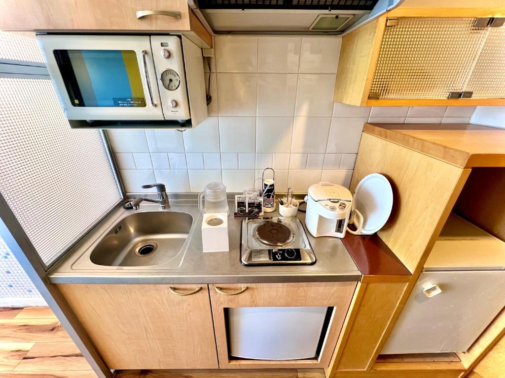 une petite cuisine avec un évier et un micro-ondes dans l'établissement Hotel Aligator -Adult Only-, à Hatsukaichi