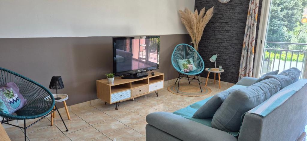 un salon avec un canapé bleu et une télévision dans l'établissement Gîte " La Petite Compsoise ", à Comps