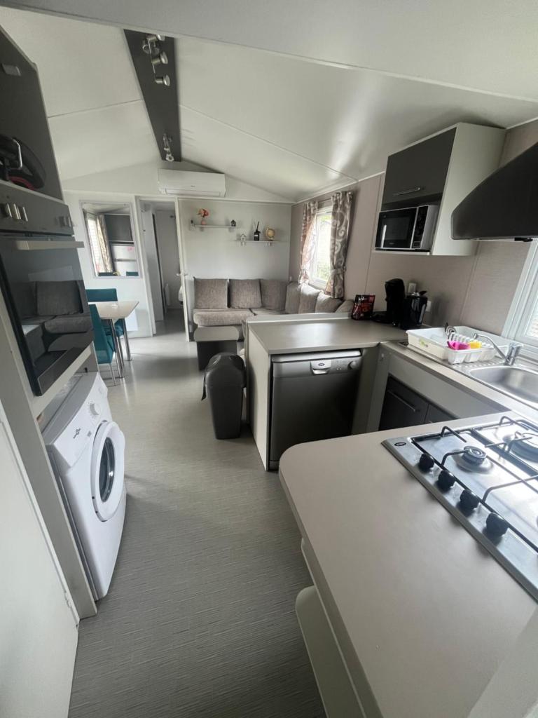 une cuisine et un salon avec une cuisinière et un four dans l'établissement Mobil home spacieux 6-8 pers, camping 4 étoiles, la Carabasse, à Vias
