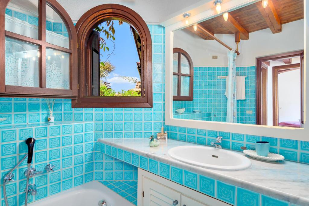 La salle de bains est pourvue de carrelage bleu, d'une baignoire et d'un lavabo. dans l'établissement Villa Miramar, à Puntaldia