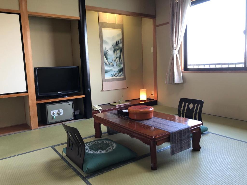 un salon avec une table et une télévision dans l'établissement 坂本屋旅館, à Kyōtango