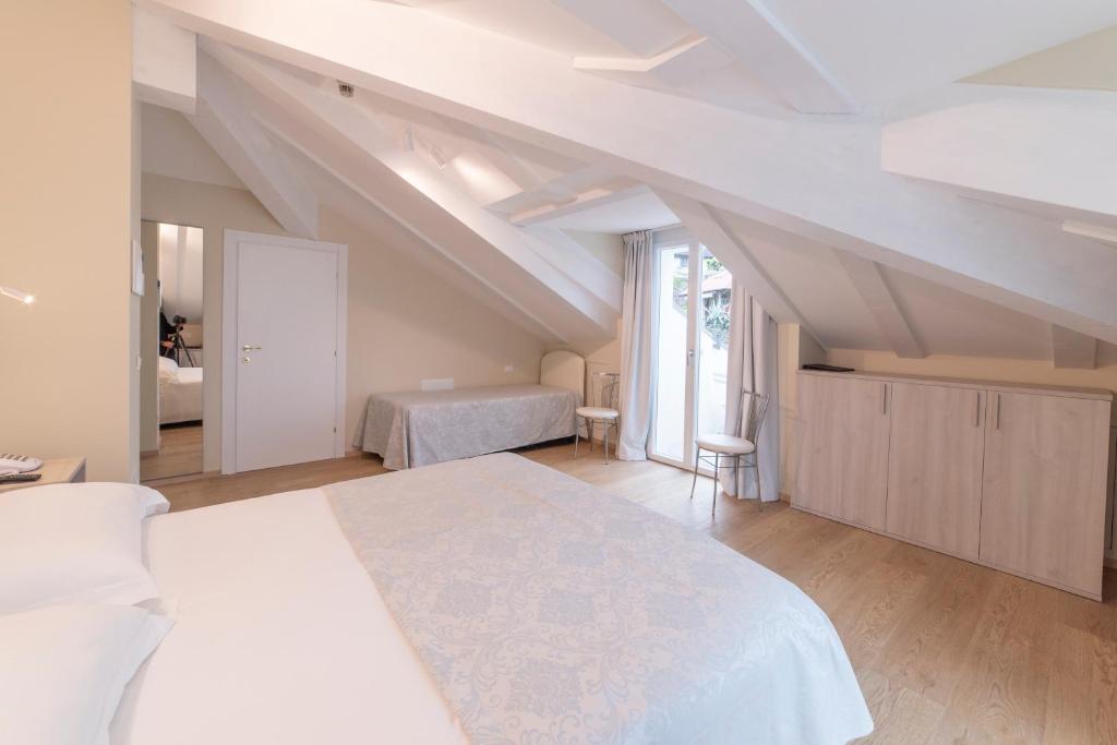 - une chambre mansardée avec un grand lit blanc dans l'établissement Hotel Due Palme, à Mergozzo