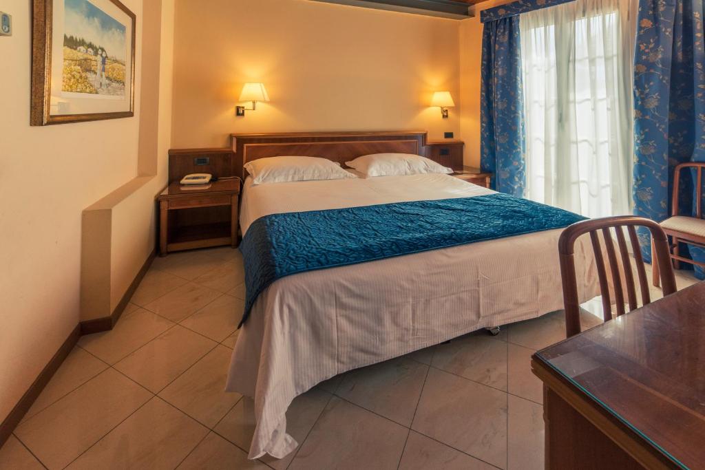 une chambre avec un grand lit avec une couverture bleue dans l'établissement Hotel Bettina, à Mergozzo