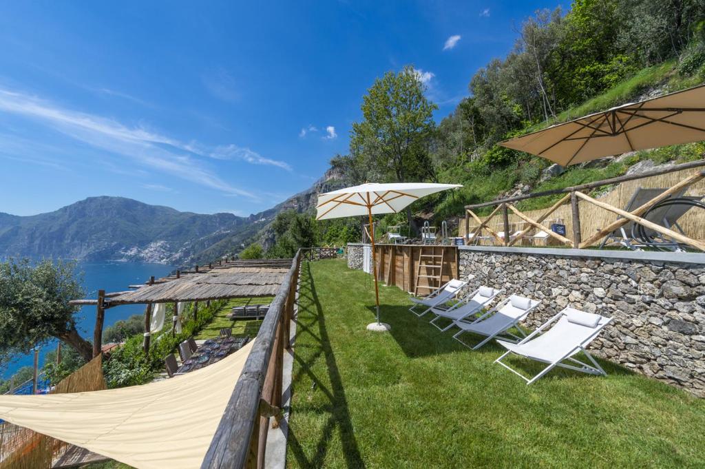 un groupe de chaises et de parasols sur l'herbe dans l'établissement Casa Punta Di Diamante - 300 stairs to the Paradise!, à Praiano
