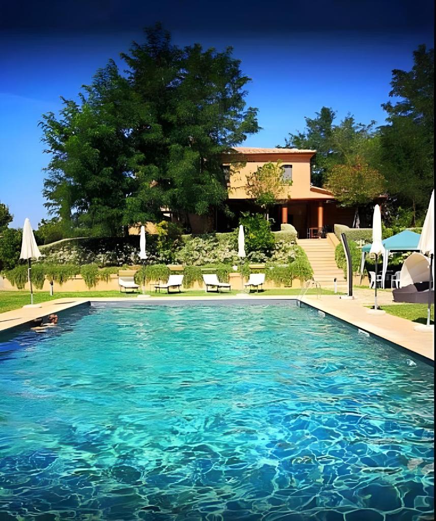 une grande piscine avec chaises et parasols dans l'établissement Macchie San Vincenzo - Villa Privata con Piscina e Giardino ad uso esclusivo o camere, à Chiusi